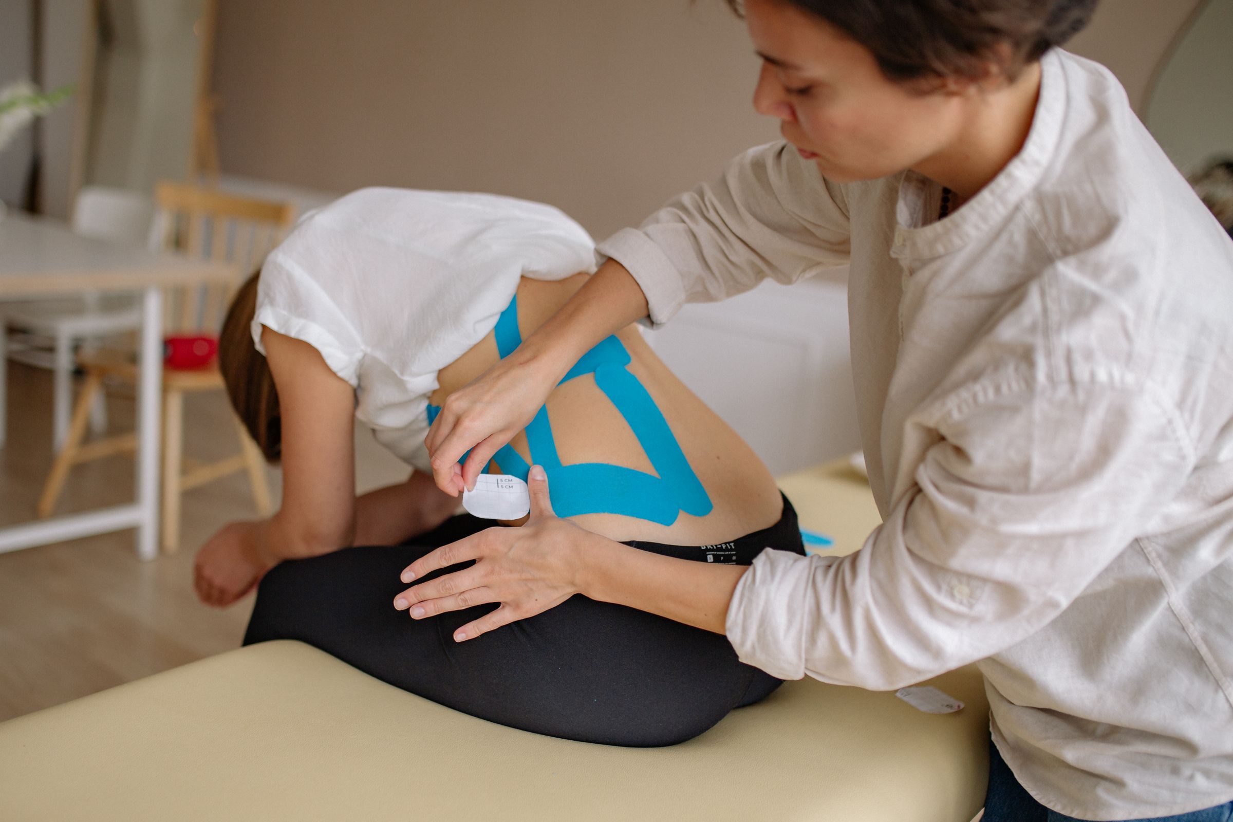 Kiropraktor hjälper patient med ryggövningar under rehabilitering