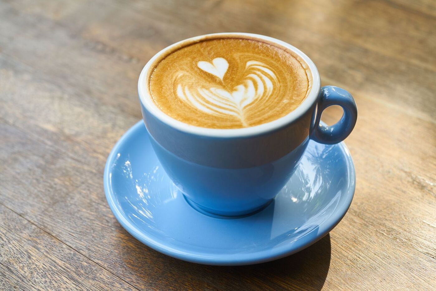 Latte art i en blå kopp på ett träbord i ett Stockholmskafé