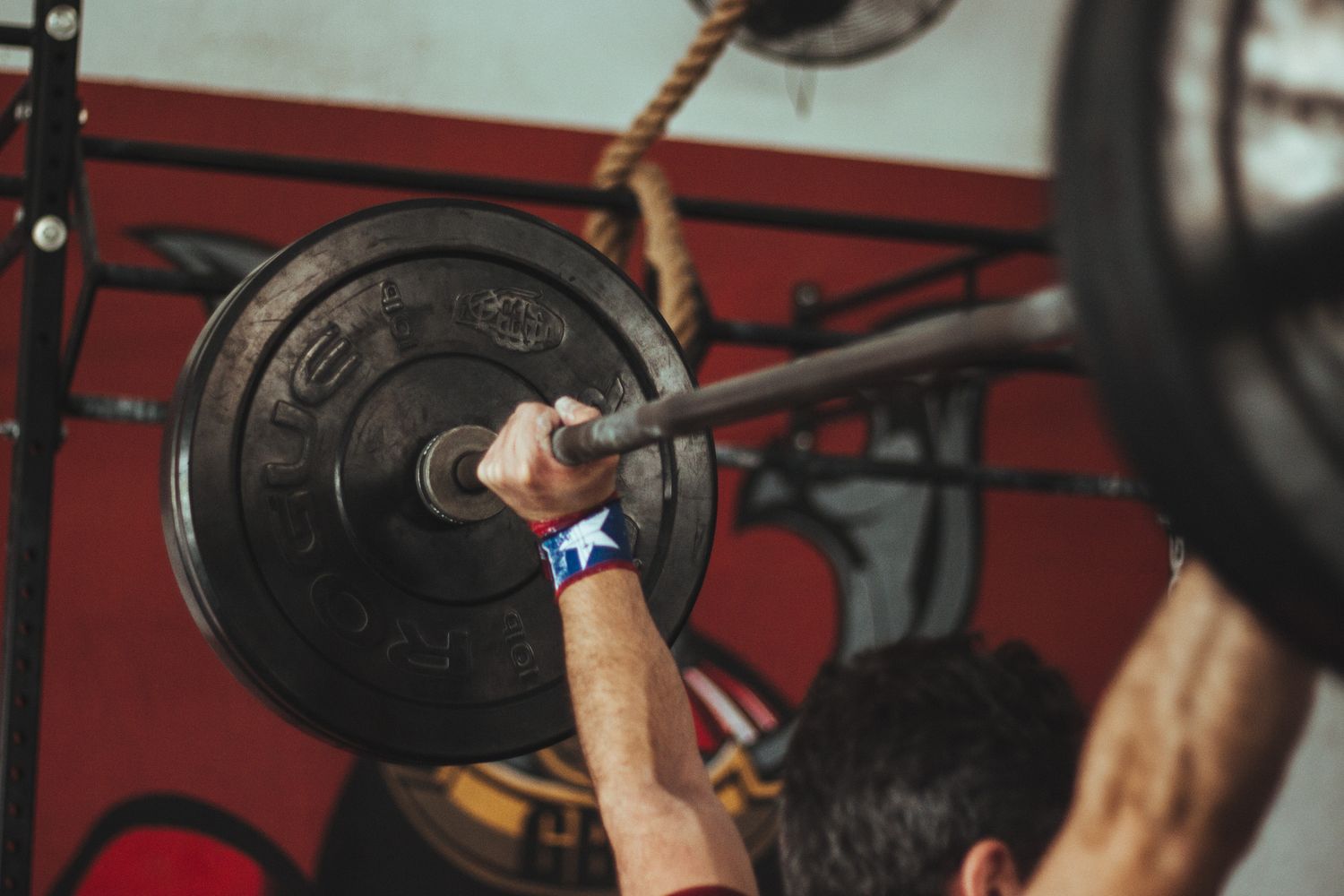 Person lyfter skivstång under styrketräning på gym