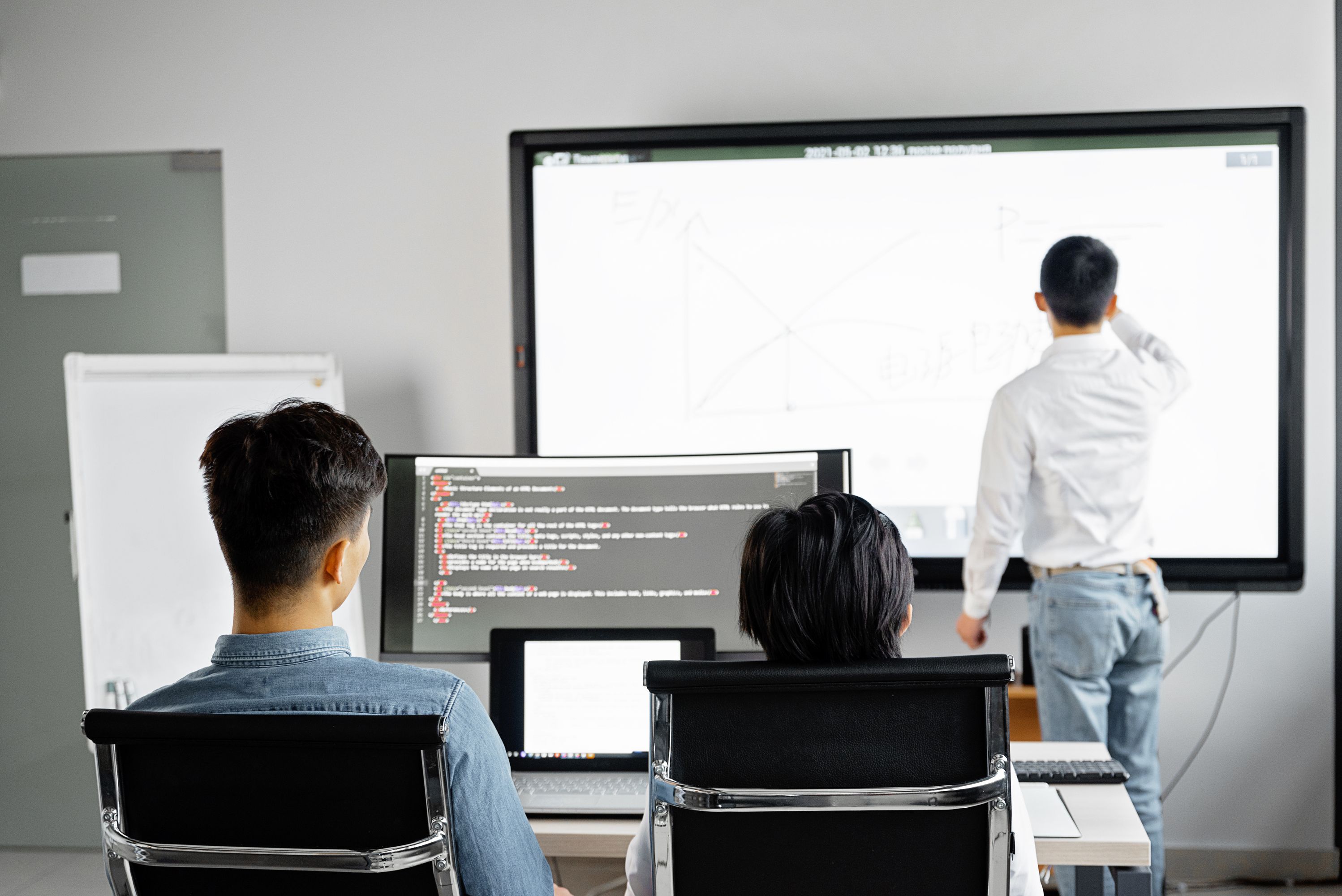 IT-team presenterar kod och systemarkitektur på storbildsskärm i Stockholm