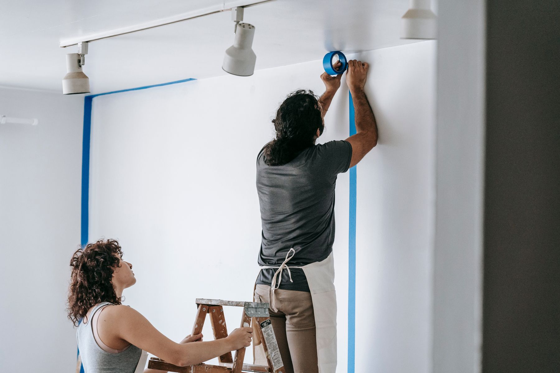 Målare rullar färg på en vägg under en lägenhetsrenovering i Stockholm