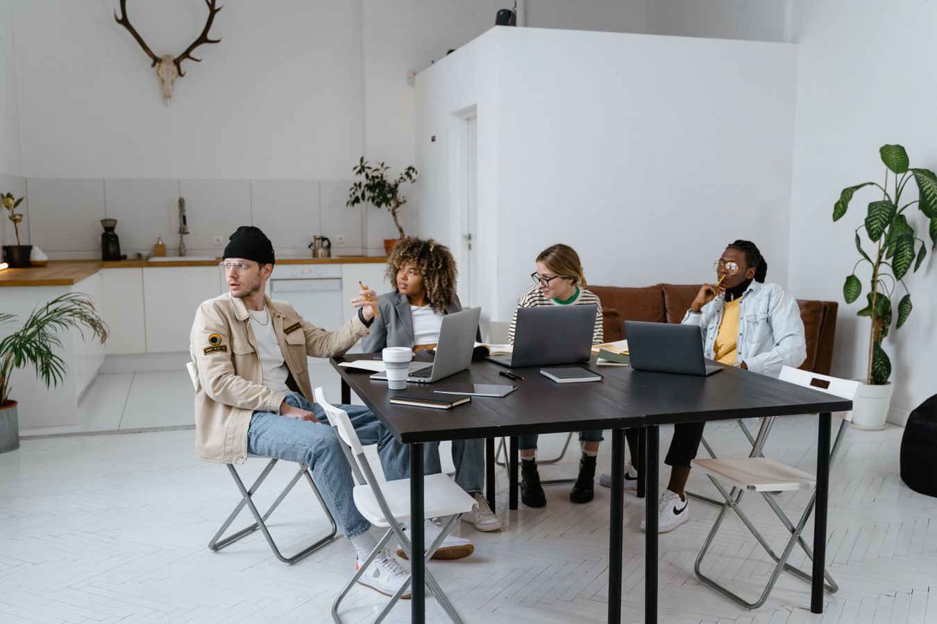 Startup-team diskuterar produktstrategi runt ett bord med laptops i ett coworking-kontor