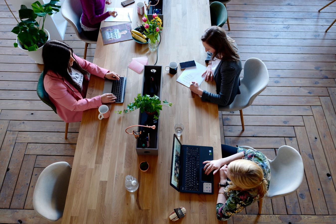 Team i ett coworking-kontor arbetar tillsammans vid laptops sett uppifrån