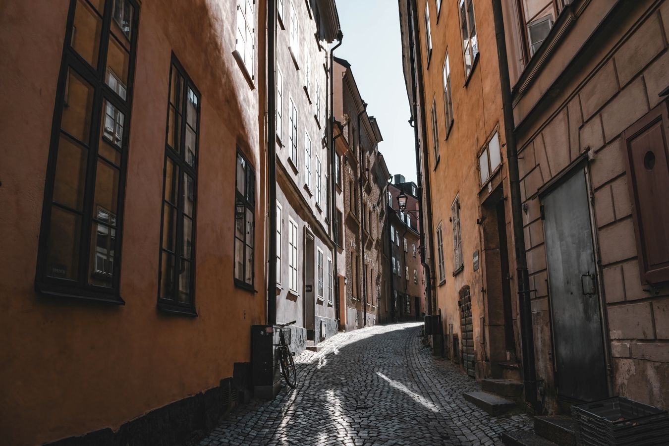 Smal gränd i Gamla Stan med gulockrafärgade fasader och kullersten, typisk för kvarteren kring Västerlånggatan
